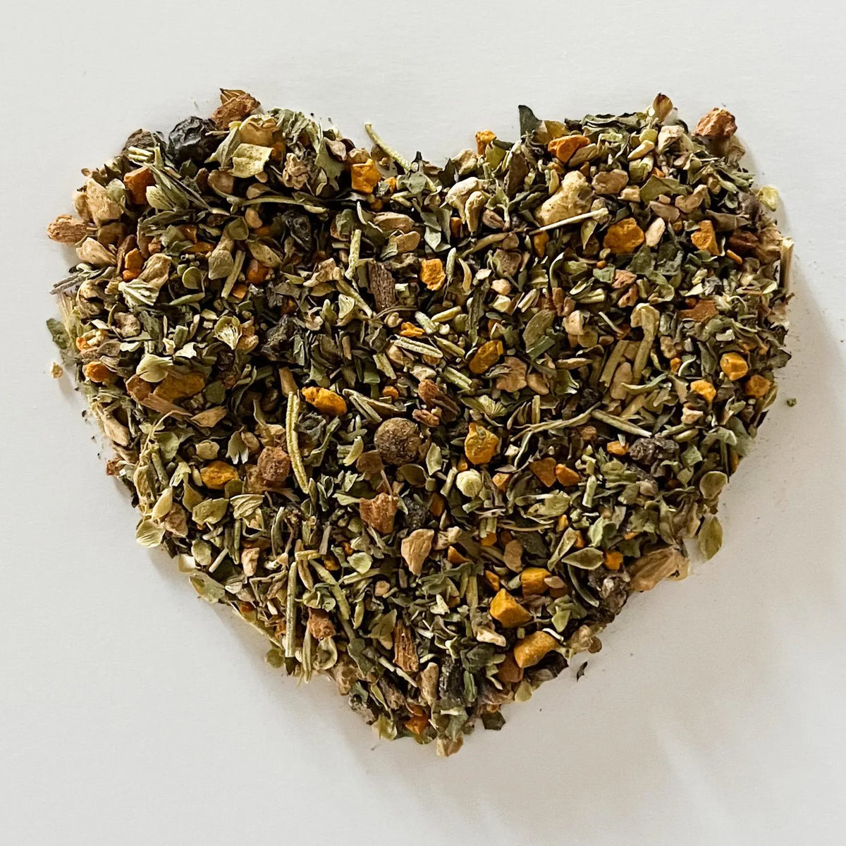 Heart-shaped pile of dried herbs on a white background