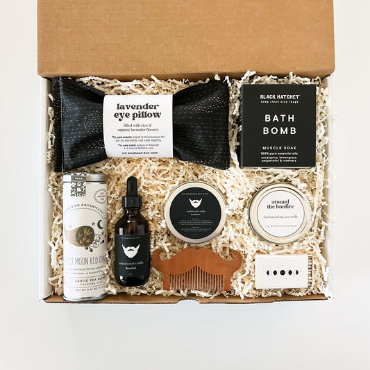 Black & White Men’s Curated Gift Box. Includes lavender eye pillow, bath bomb, harvest moon red chai tea, beard care kit, around the bonfire soy candle, and moon phases matchbox. ￼