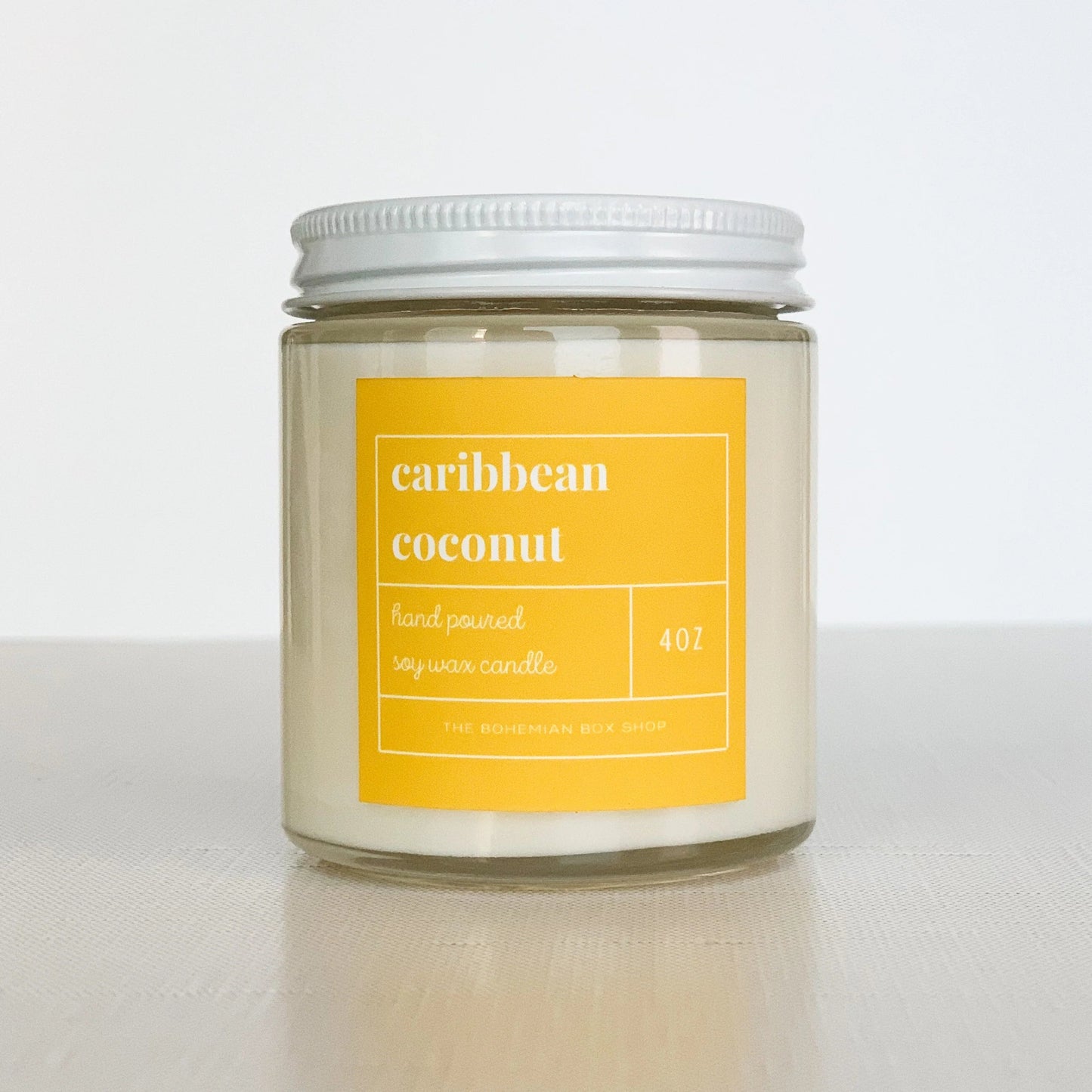 4 ounce Caribbean coconut soy candle with yellow label, clear jar, and white lid.