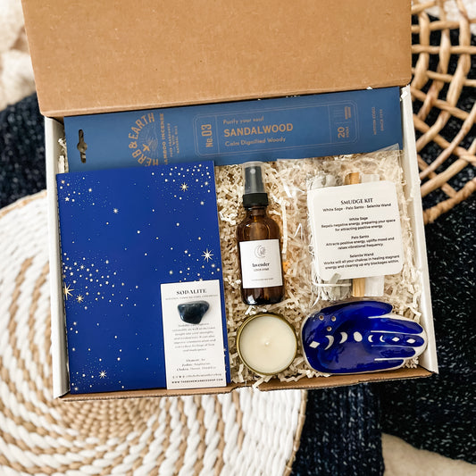 Celestial Spiritual Gift Set Box - Energy Cleansing Kit. Includes incense and hamsa holder, blue celestial journal, sodalite, lavender linen spray, soy candle, and smudge kit. 