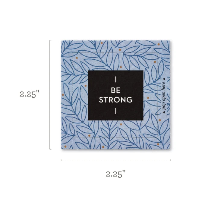 A square decorative card or coaster with a light blue and navy leaf pattern, featuring a central black square with the text 'BE STRONG' in white. The image includes dimension lines indicating a size of 2.25"