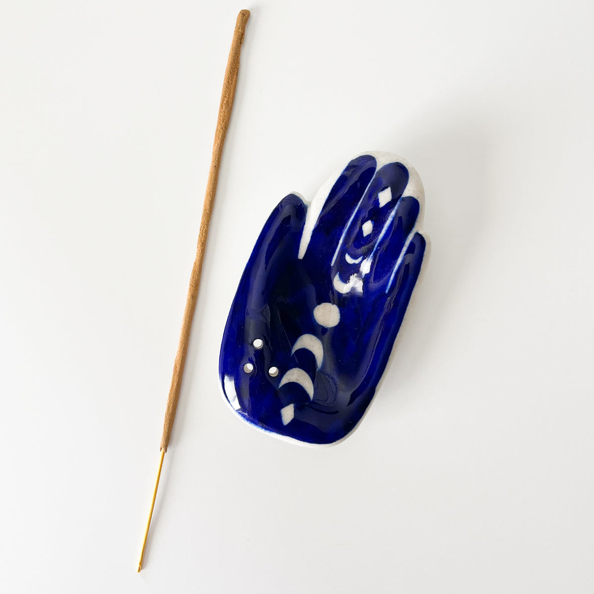 Blue Hamsa Moon Phase Incense Holder laid next to a incense