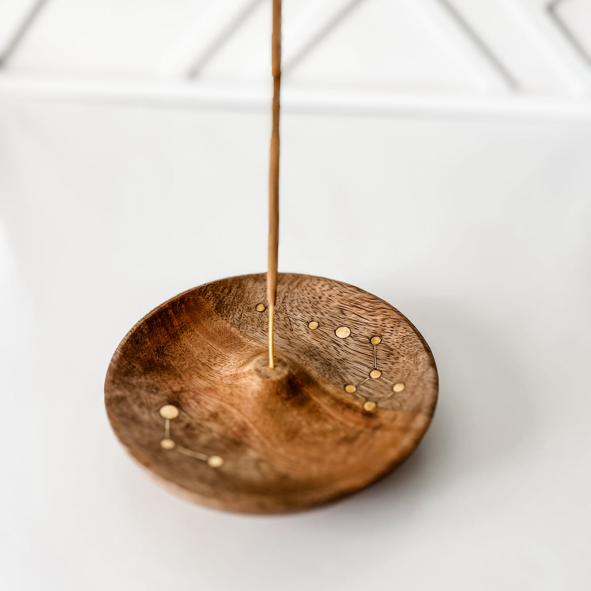 Celestial Round Incense Holder on a white and textured background with an incense stating up