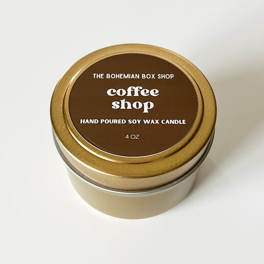 Candle in a tin with a brown lid labeled 'Coffee Shop' from The Bohemian Box Shop on a white background.