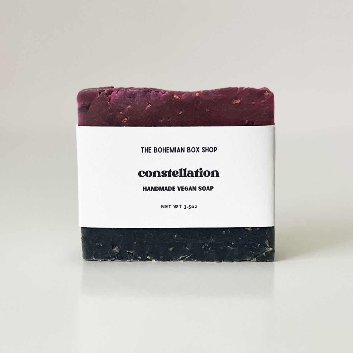 A purple handmade vegan soap bar with 'The Bohemian Box Shop' and 'CONSTELLATION' written on the packaging, indicating the scent of the soap.