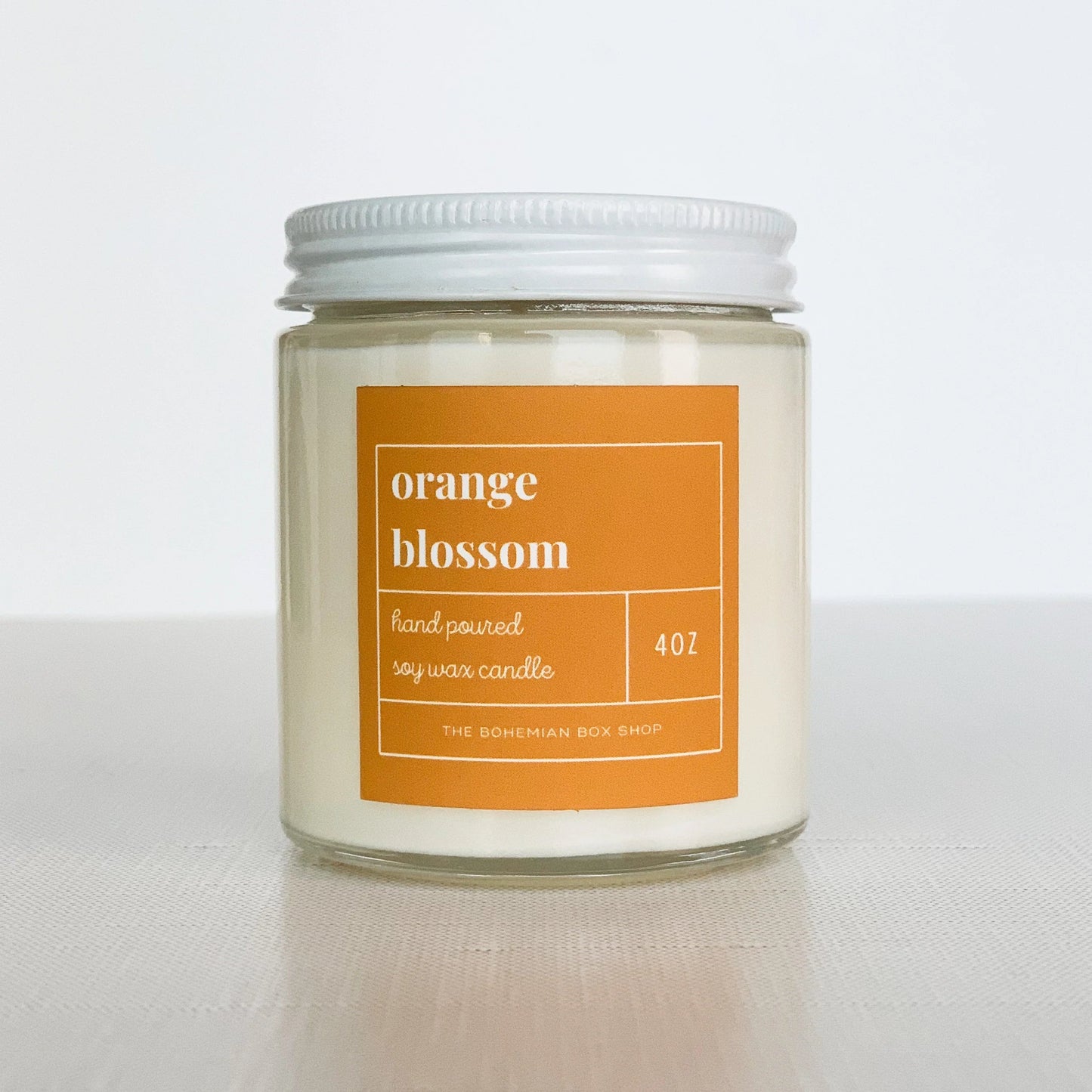 4 ounce orange blossom soy candle with orange label, clear jar, and white lid.