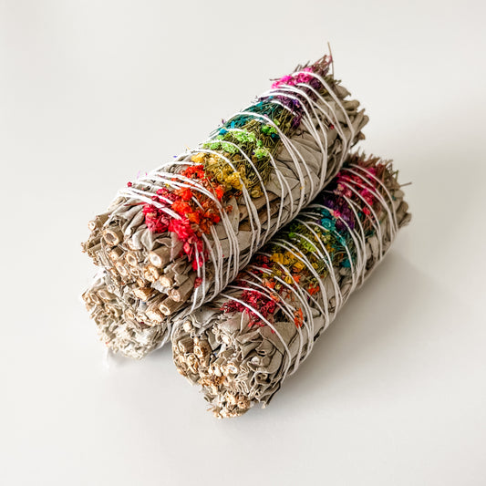 three bundles of 4-inch white sage smudge sticks adorned with colorful floral decorations, bound by string.