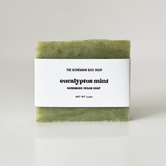 A bar of Eucalyptus Mint handmade soap with a white label that reads 'the bohemian box shop / eucalyptus mint / handmade vegan soap'.