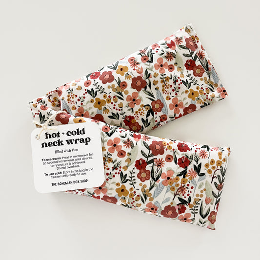 a hot and cold neck wrap with a floral pattern on a red background, packaged and labeled for use as hot and cold therapy. Made by The Bohemian Box Shop