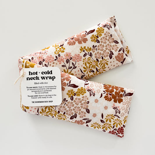 A Hot and Cold Neck Wrap with a floral pattern in earth tones, displayed on a white background, packaged with a label.
