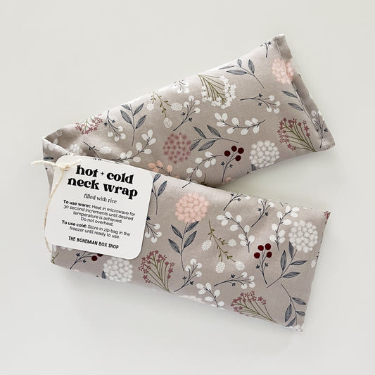 A floral patterned hot and cold neck wrap made of cotton, with a tag indicating it is from The Bohemian Box Shop.