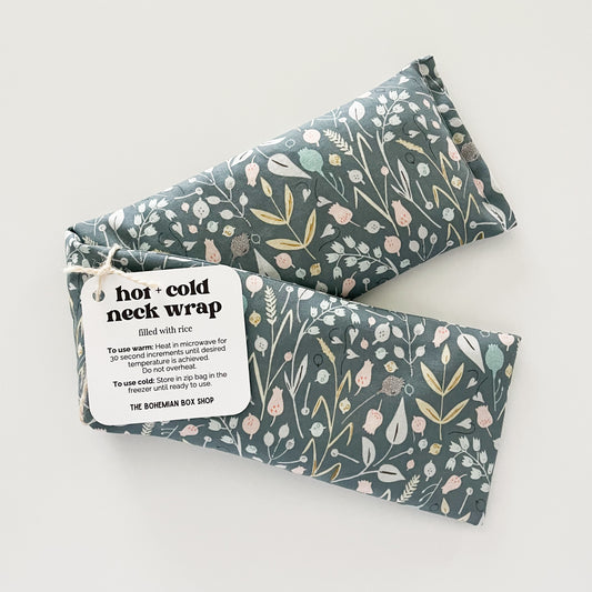Two Hot and Cold Neck Wraps with a floral pattern on a gray background, packaged with labels.