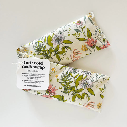 white, green, purple and pink Floral patterned hot and cold neck wrap with a label on a light background