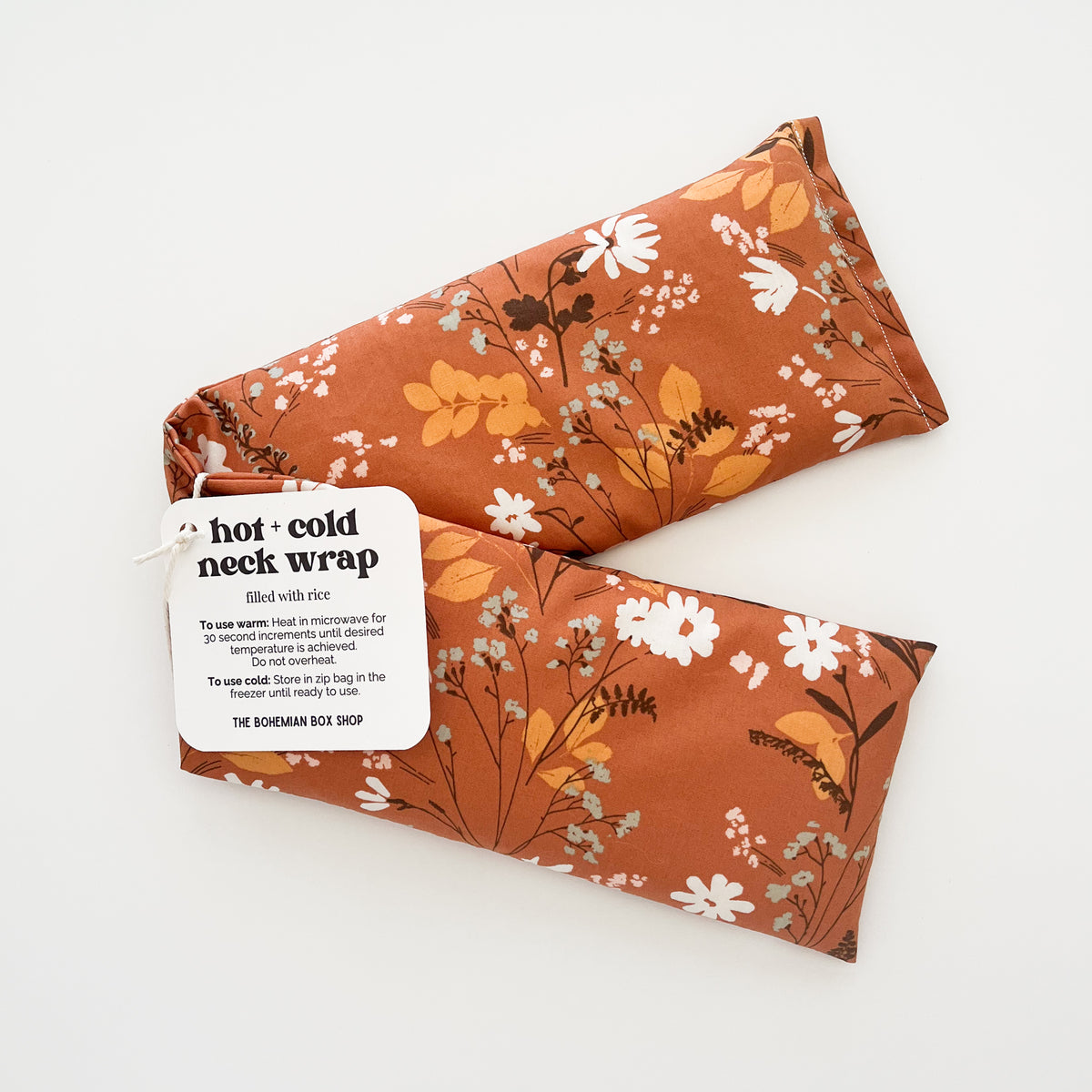 A hot and cold neck wrap with a rust-orange floral pattern, shown on a clean white background. 