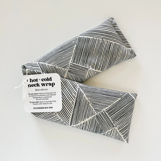 a black and white striped hot and cold neck wraps with a label on a light gray background