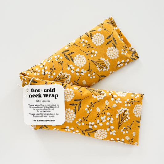 Yellow floral hot and cold neck wrap with a label on a white background