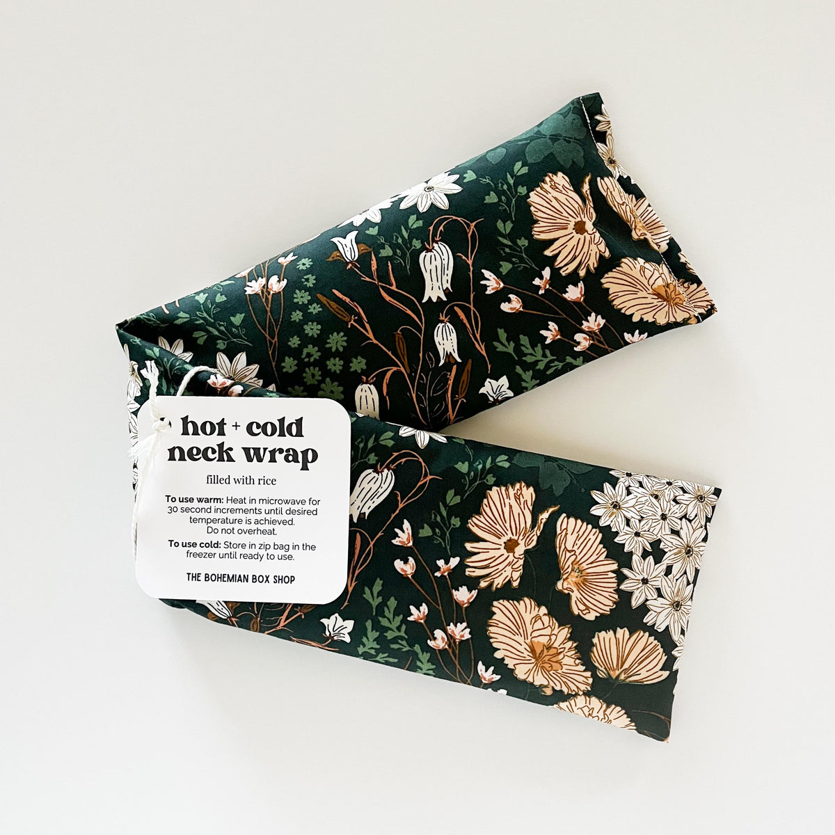 Dark green floral patterned hot and cold neck wrap with label on a white background