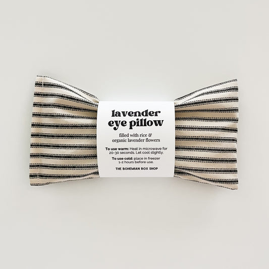 lavender eye pillow filled with rice and organic lavender flowers in an ivory and black stripe fabric on a white background