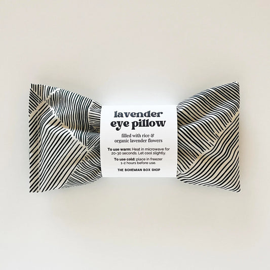 Lavender eye pillow with white and black stripes with packaging on a white background