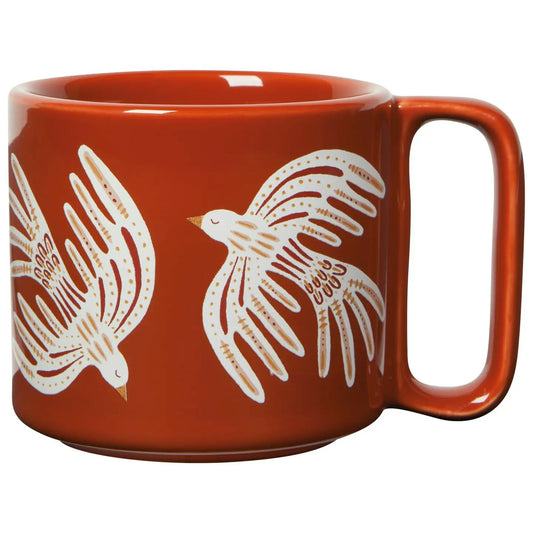 A red ceramic mug with white and gold bird patterns.