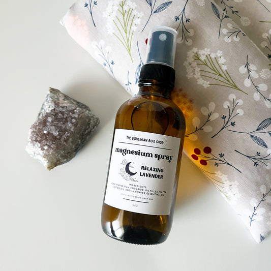 Bottle of relaxing lavender magnesium spray in an amber spray bottle with a black spray pump with a label on a white surface with decorative elements.
