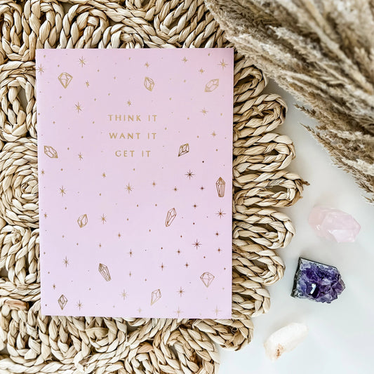 a light purple journal with 'think it, want it, get it' on the front with gold crystals on a boho background