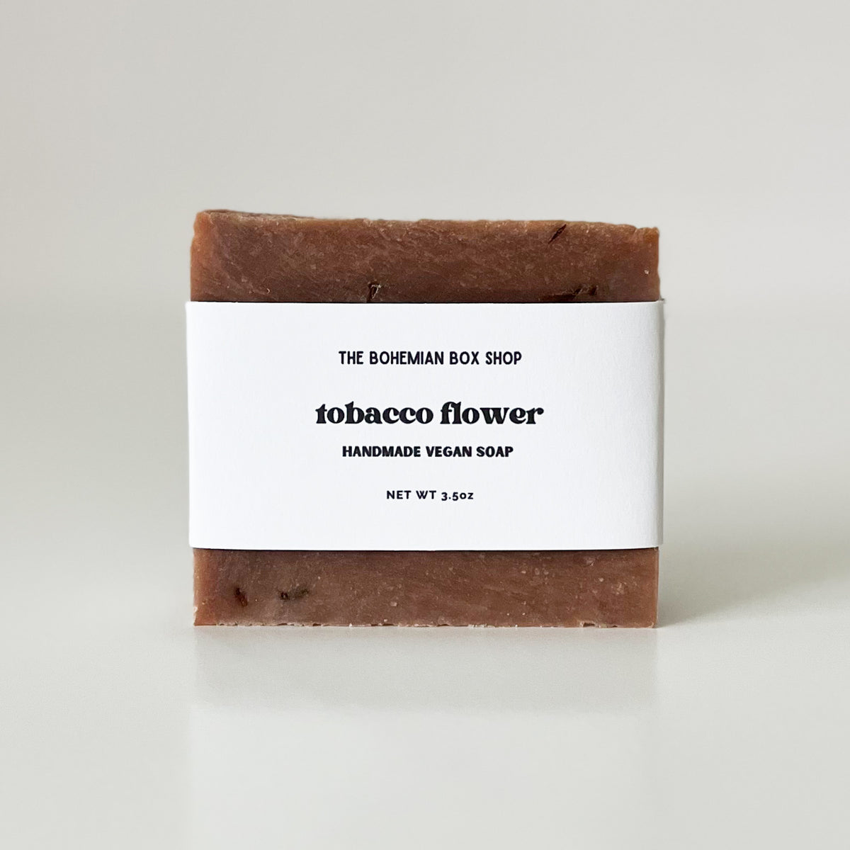 A bar of handmade vegan soap with 'The Bohemian Box Shop' and 'Tobacco Flower' label on a white background.