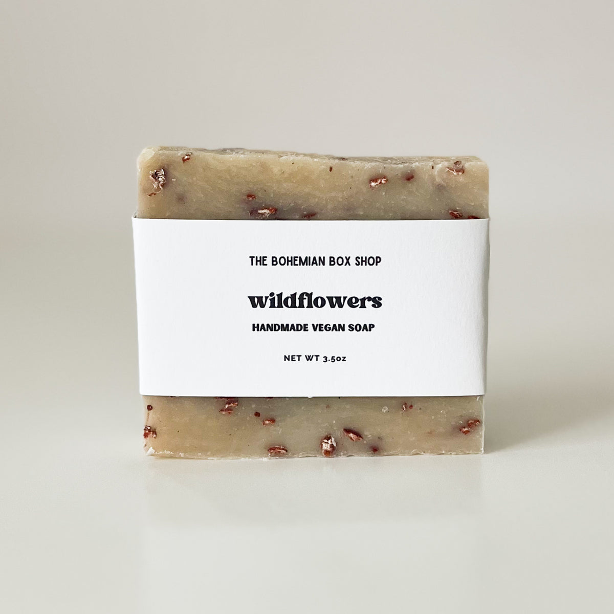 A bar of handmade vegan soap with 'Wildflowers' labeled on the packaging, and made by The Bohemian Box Shop