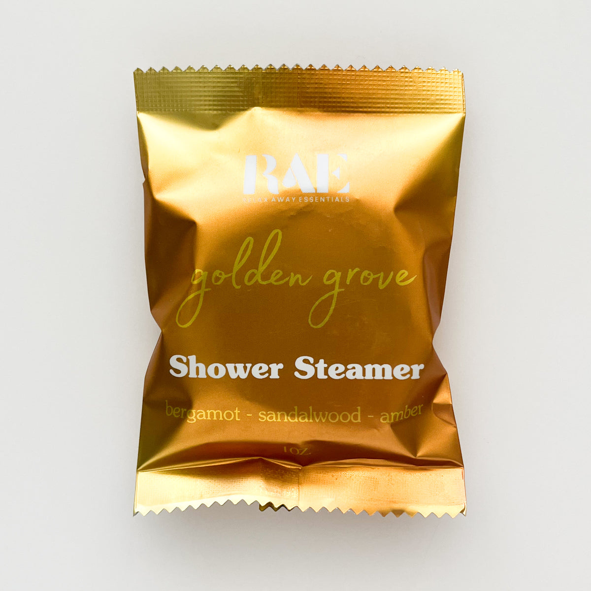 A single metallic gold shower steamer packet from RAE (Bergamot, Sandalwood, and Amber) on a clean white background.