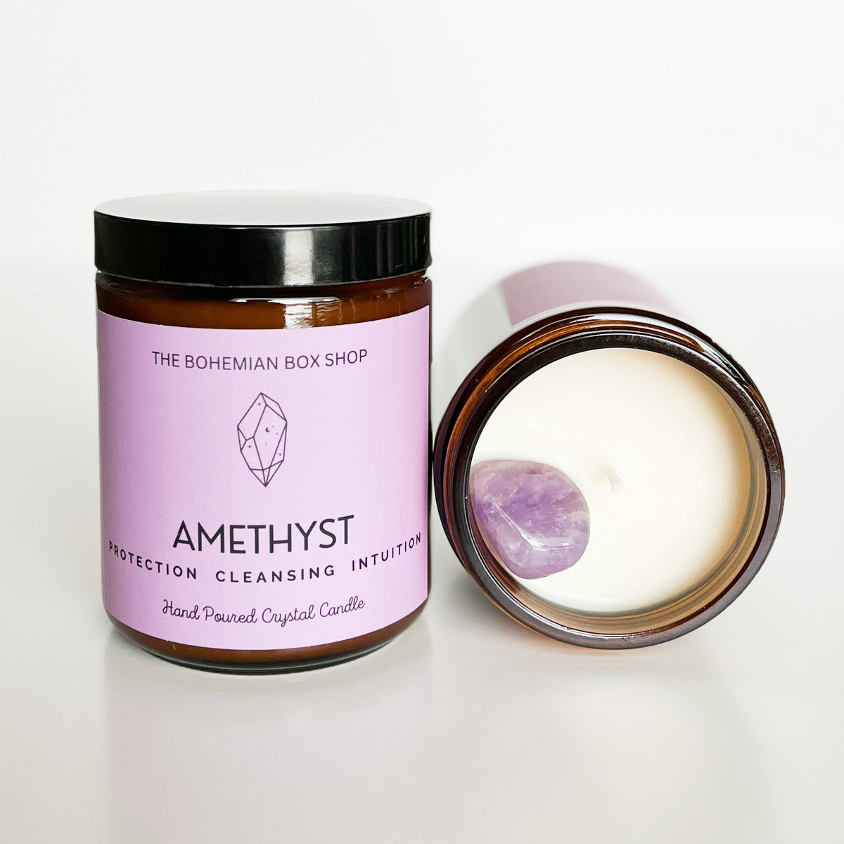 A purple candle labeled 'Amethyst Protection, Cleansing, Intuition' with its lid off, showing the inside of a candle with an amethyst on top