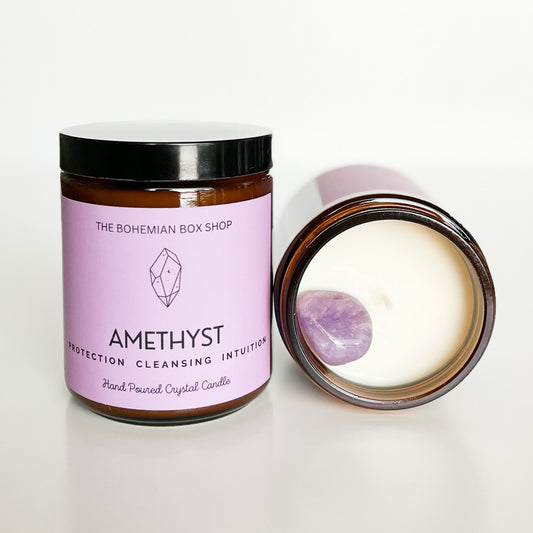 A purple candle labeled 'Amethyst Protection, Cleansing, Intuition' with its lid off, showing the inside of a candle with an amethyst on top