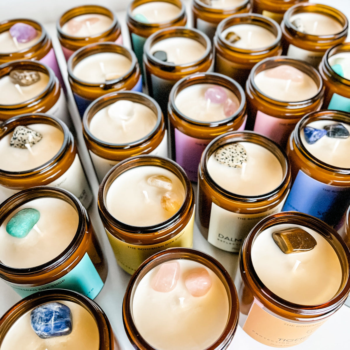 assorted crystal soy candles in amber jars topped with different crystals 