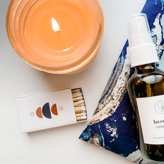 Boho Style Match Box on a background with a lit candle, lavender linen spray and lavender eye pillow
