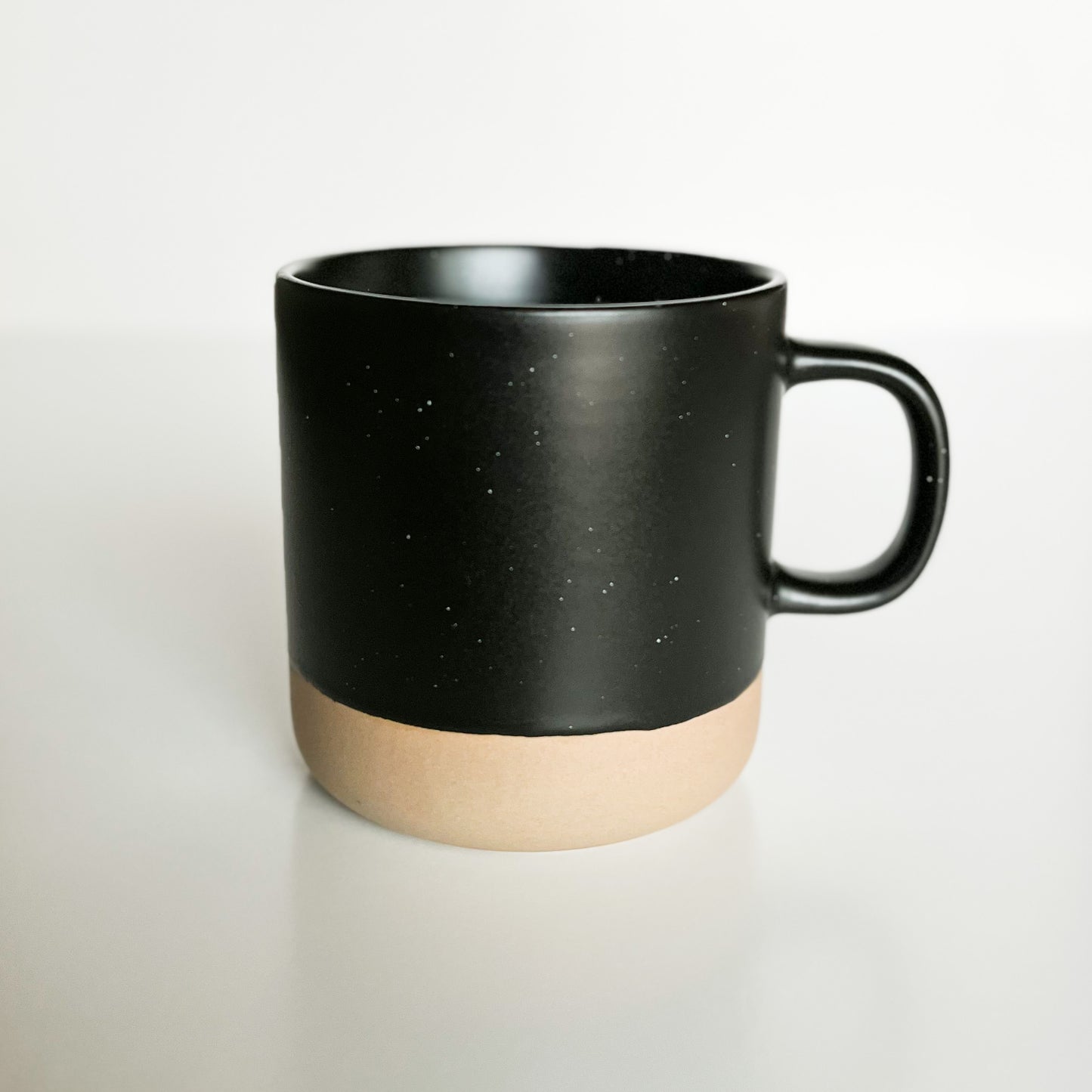 black speckled ceramic mug with neutral clay bottom
